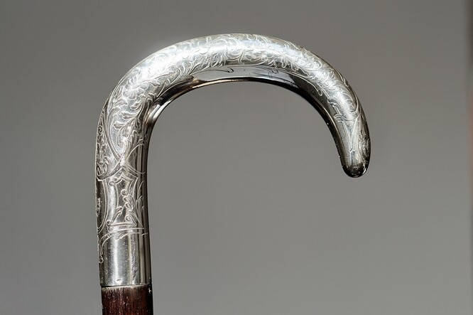 A Polish walking-stick, after 1920. Curved silver handle with a depiction  of the goddess of victory Nike, supported by Akanthus leaves, silver  hallmarks on the right hand side. Shaft of ebony, the